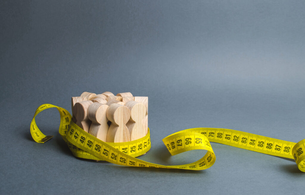 Measuring tape with wooden stick figures inside of it being tied up. This represents measuring user data. 